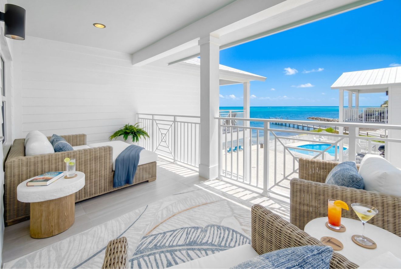 Balcony lounge with wicker daybed overlooking the pool and ocean