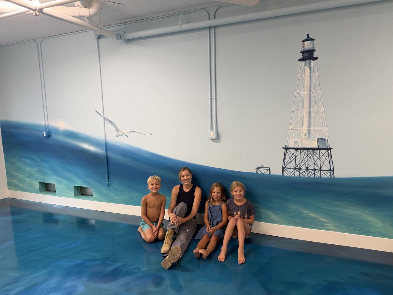 Guests posing by the lighthouse mural in the game room