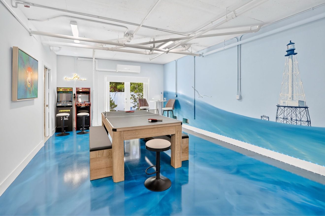 Renovated game room with table tennis, arcade machines, and a lighthouse mural